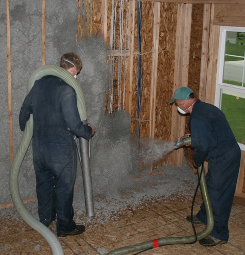 Two men spraying insulation onto wall cavities