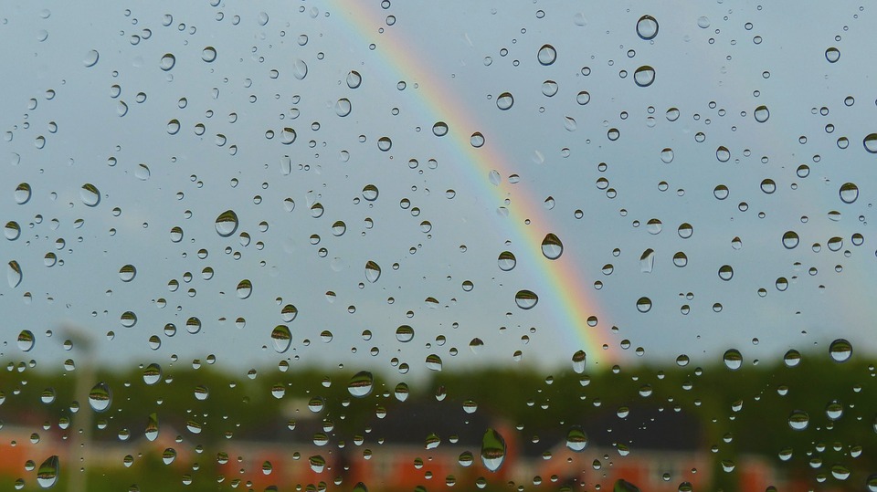Rainbow behind a glass window with water droplets