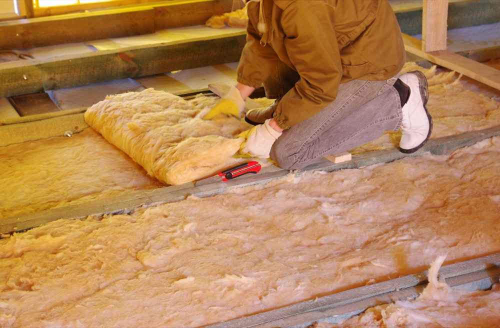 man lays attic insulation in existing home