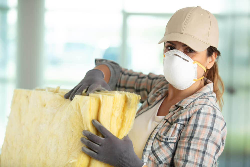 Female worker with mask and gloves carrying insulation