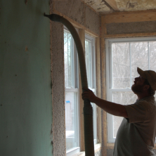Technician blowing insulation into a wall covered in sheetrock