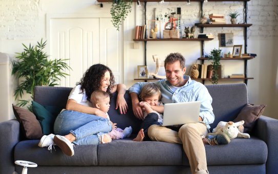 Relaxed comfortable family sitting on a couch looking at something on a laptop