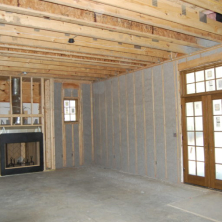 Spacious front room of an office building with new gray cellulose insulation in between the studs