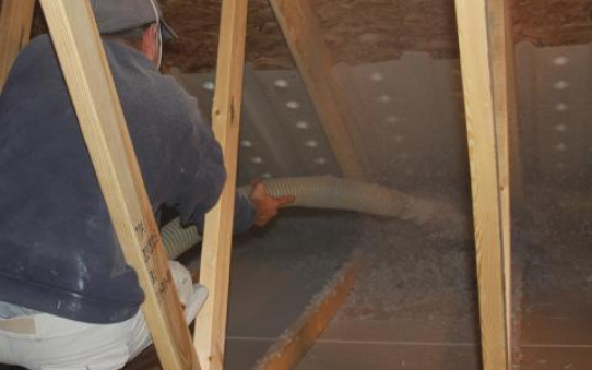 Man blowing insulation into an attic
