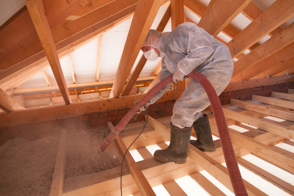 Worker blowing cellulose insulation into a residential attic