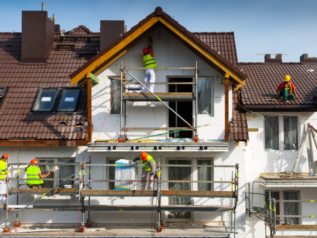 Workers installing thermal insulation on the facade of a house