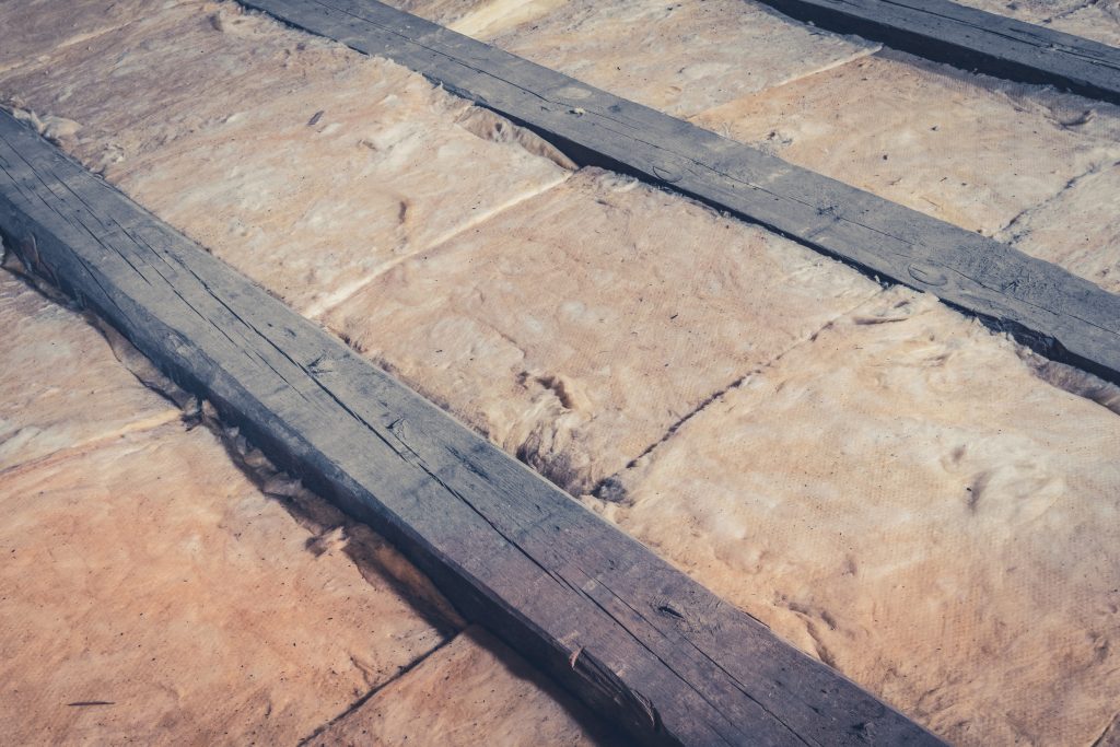 Older home attic room with exposed wood beams and insulation