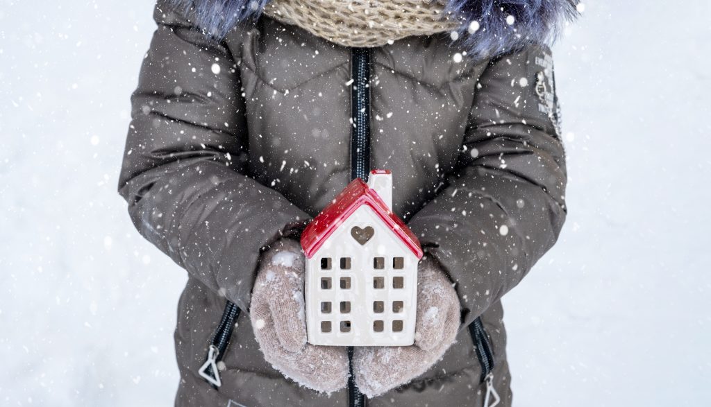 Miniature model of a cottage in winter and woman in winter coat