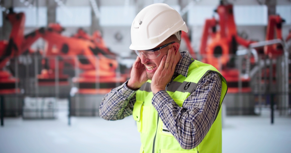 Technician covering ears due to loud facility environment
